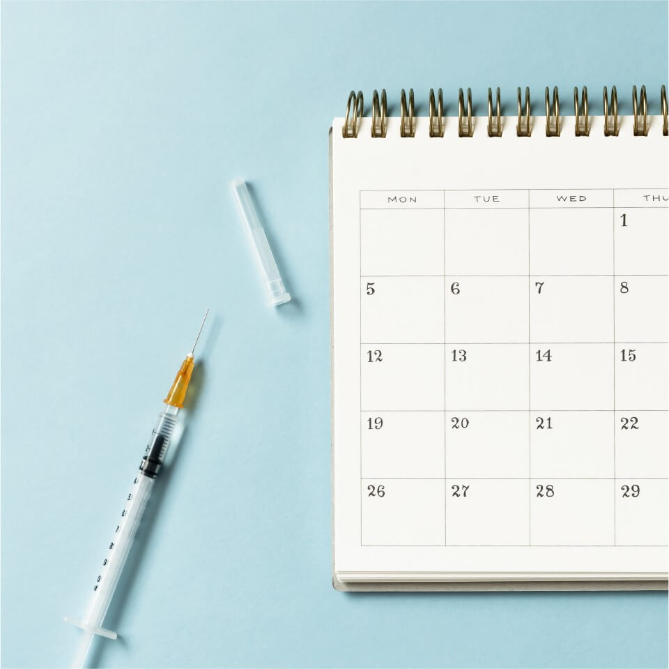 Vaccine shot and calendar on a table