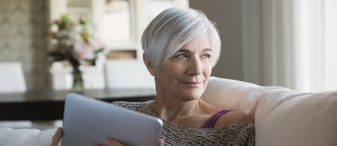woman with white hair reading on iPad